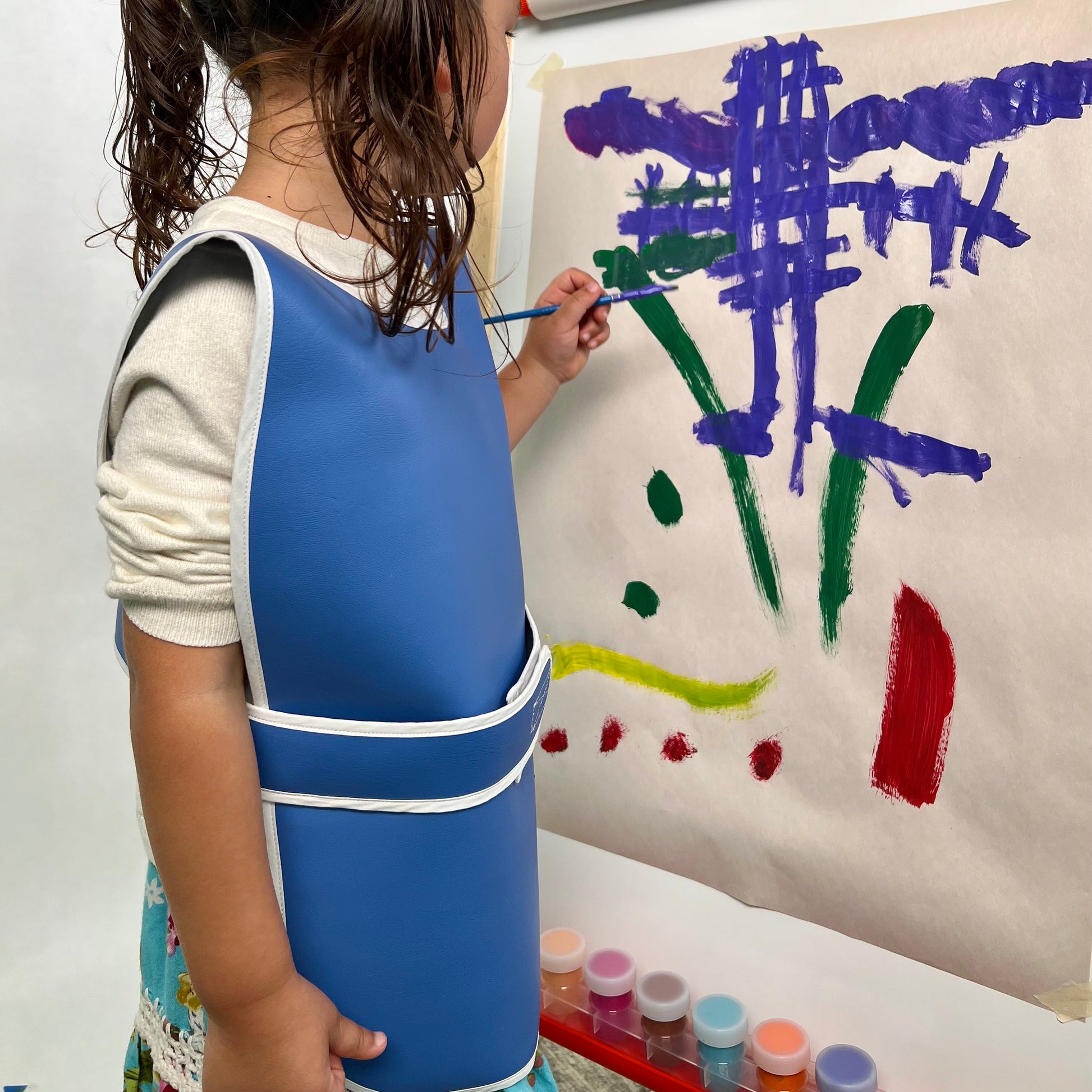 Child painting with blue durable washable waterproof vinyl rolled Primary Montessori apron